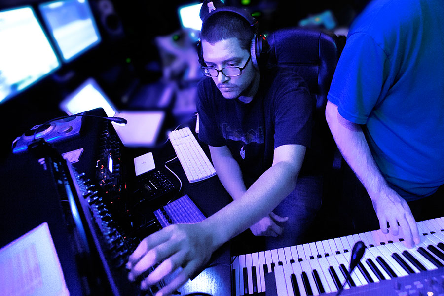 USV Electronic Music Production students working hands-on in the studio with dramatic purple lighting.