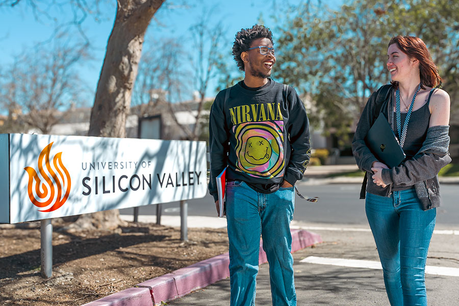 USV students walking by the campus sign, talking and smiling at each other.